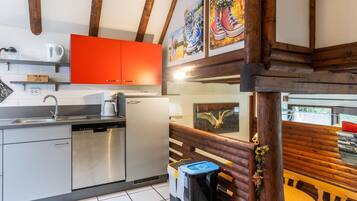 A modern kitchen with stainless steel appliances, a red cabinet, and wooden beams.