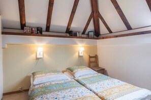 Ein Schlafzimmer mit zwei Betten, Holzbalken an der Decke und Wandleuchten.