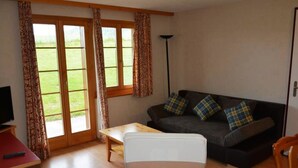 A living room with a sofa, a chair, a table, and a TV. - Anne (Tiefparterre) Appartement/Fewo, Dusche oder Bad, WC 6-Bettwohnung by Interhome (Gstaad)