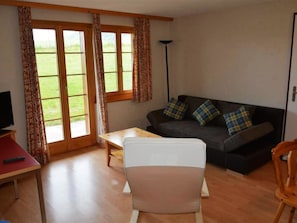 Ein Wohnzimmer mit einer Couch, einem Sessel, einem Tisch und einem Fernseher.