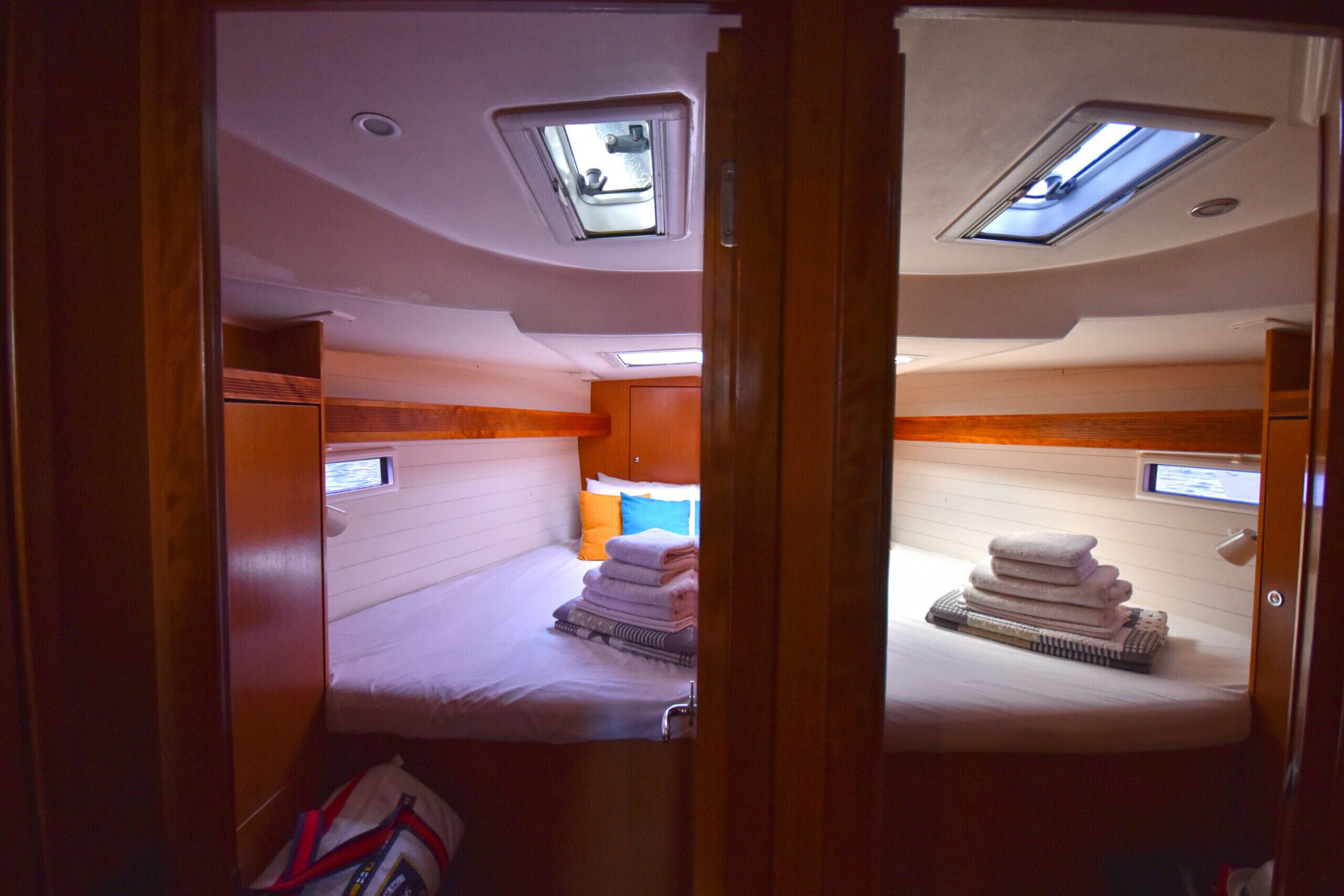 A compact bedroom with a bunk bed, a skylight, and a small window.