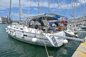 A boat docked at a marina with multiple masts, a steering wheel, and a lifebuoy.