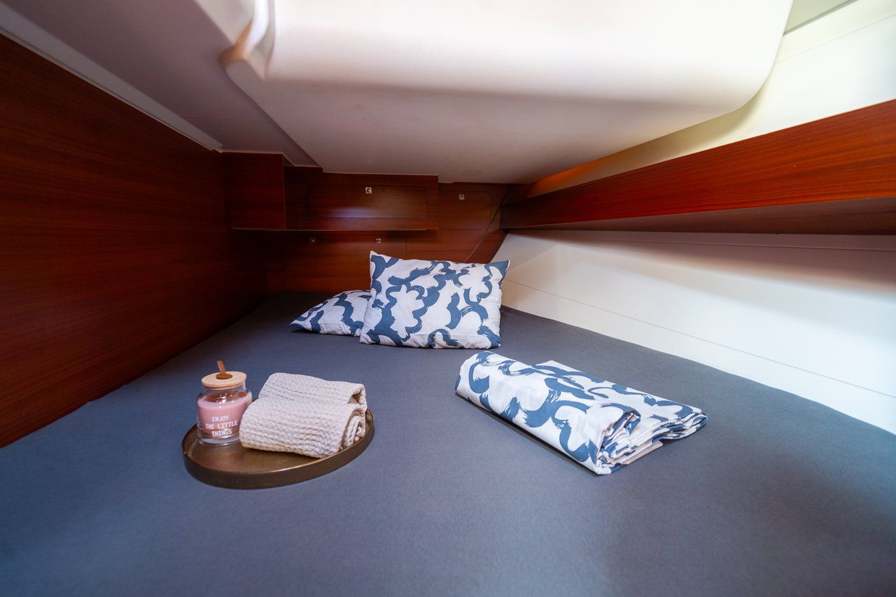 Ein kleines Zimmer mit einem Bett, Kissen, einem kleinen Tisch mit Kerze und einem Handtuch.