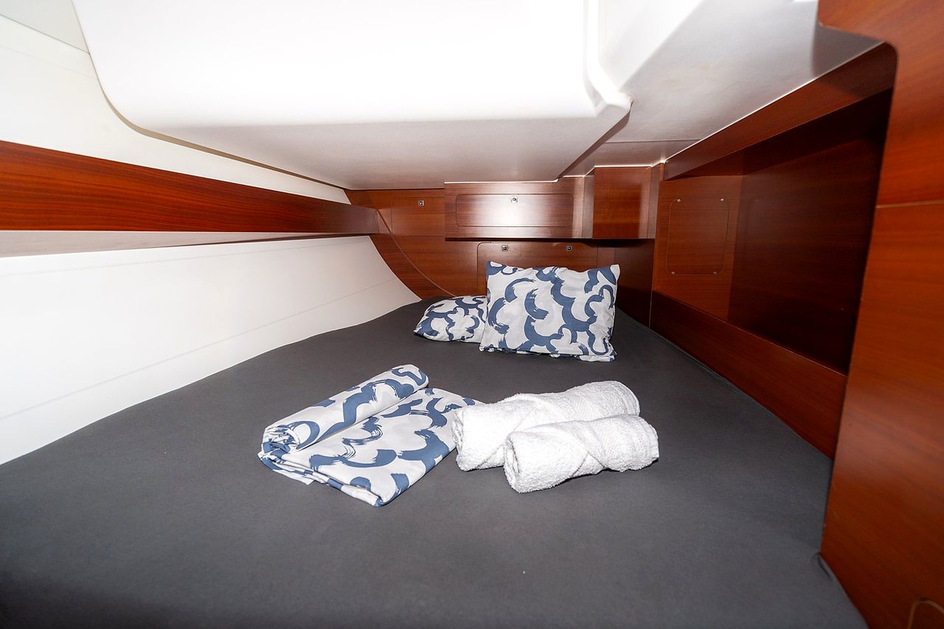 A compact cabin with a single bed, two pillows, and neatly folded towels.