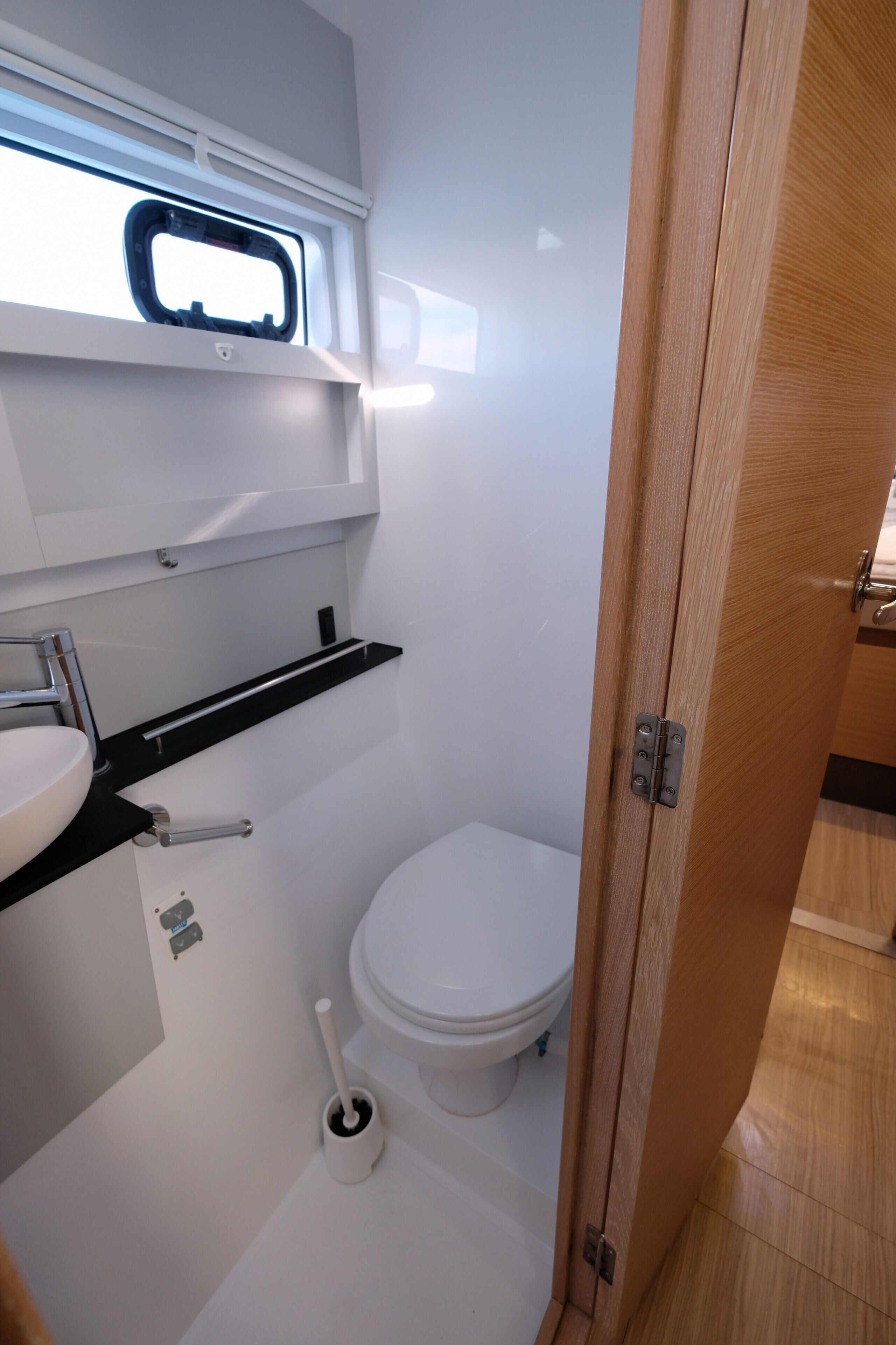Ein kleines Badezimmer mit Toilette, Waschbecken und einem Fenster über dem Waschbecken.
