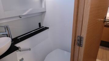Ein kleines Badezimmer mit Toilette, Waschbecken und einem Fenster über dem Waschbecken.