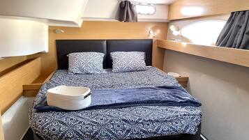 A compact bed with patterned bedding, a bedside table, and a window with curtains.