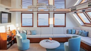 A modern interior with a sofa, chairs, a coffee table, and large windows with a view of the sea. - Sun-Kissed Sailing Adventure in Split, Croatia (Split)