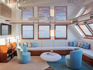 A modern interior with a sofa, chairs, a coffee table, and large windows with a view of the sea. - Sun-Kissed Sailing Adventure in Split, Croatia (Split)