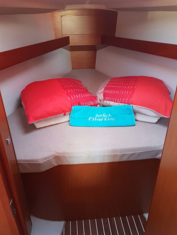 Une petite chambre avec un lit, deux oreillers et un sac bleu sur lequel est inscrit le texte « charte parfaite ».