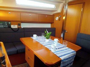 Une cabine compacte avec une table dressée pour le repas, une petite plante et un panneau de commande B&G.