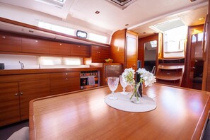 Eine kleine Küche mit Holdekor, einem Kühlschrank und einem Esstisch mit Platzdeckchen und Blumen.