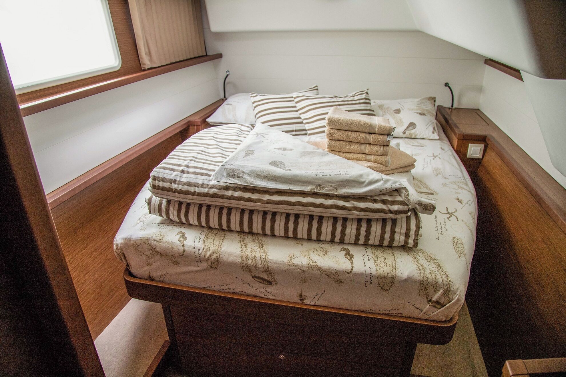 A small, cozy room with a single bed, a wooden bench, and a window with blinds.