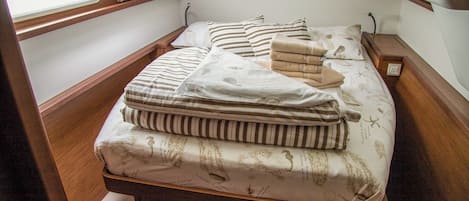 A small, cozy room with a single bed, a wooden bench, and a window with blinds.