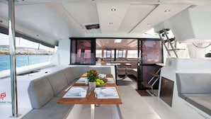 Interior moderno de un yate con comedor, cocina y zona de estar.