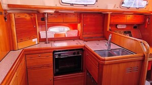 A compact kitchen with wooden cabinetry, a built-in oven, a sink, and two windows. - Sun-Kissed Sailing Adventure in Northern Croatia (Punat)