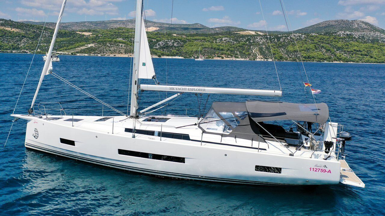 Uno yacht bianco, denominato 'MK YACHT EXPLORER' con il numero di registrazione '112759-A', su un mare calmo.