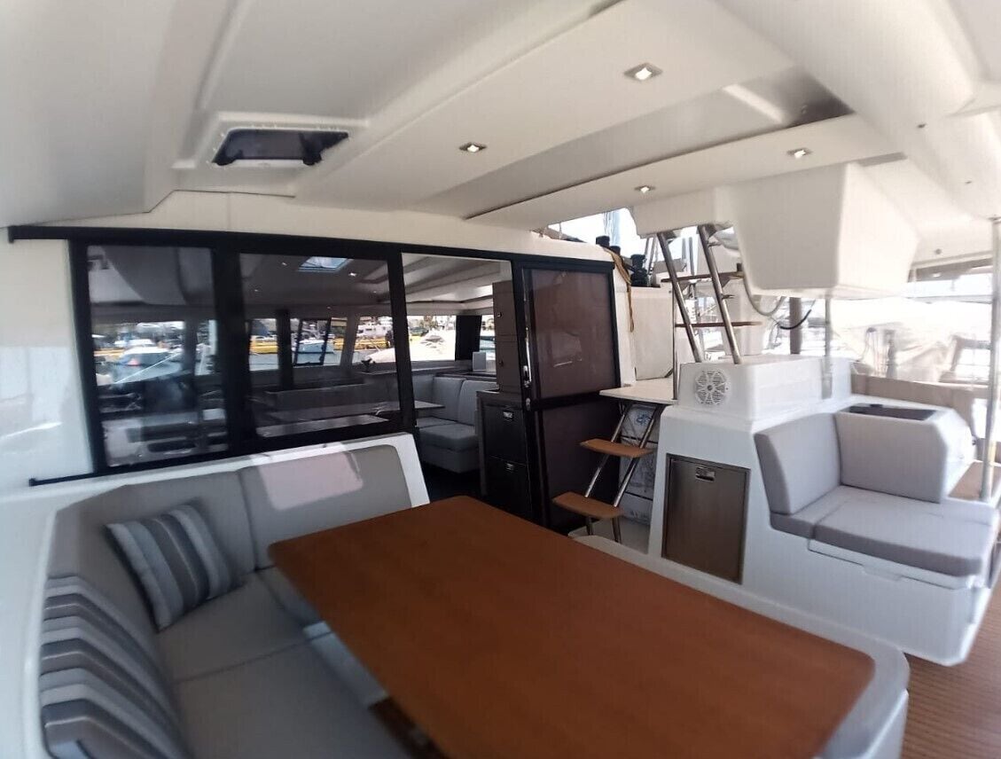 A boat interior with a dining area, seating, and a view of the outside.