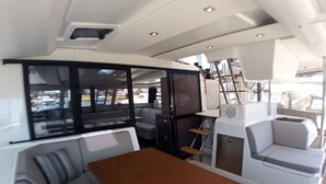 L’intérieur d’un bateau, avec un espace repas, des sièges et une vue sur l’extérieur.