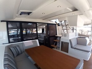 A boat interior with a dining area, seating, and a view of the outside. - Sun-Kissed Sailing Adventure in the Ionian Islands, Lefkada (Lefkada)