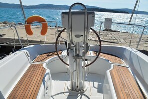 Ein Bootsdeck mit Steuerpult, Rettungsflossen und Blick auf das Meer und die Berge.