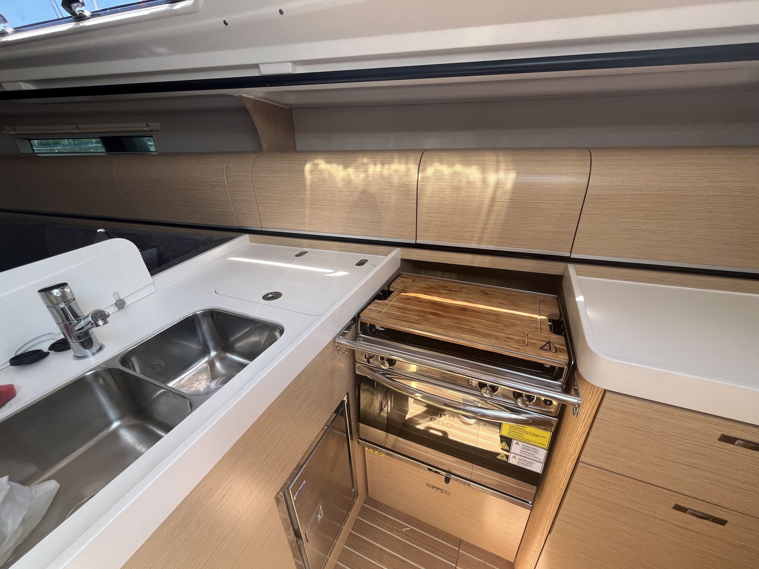 Una cocina compacta con un lavamanos de acero inoxidable, horno empotrado y muebles de madera.