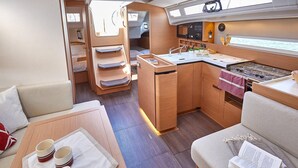 Ein kompaktes Wohnmobil-Interieur mit einer Küchenzeile, einer Essecke und einem Schlafbereich.