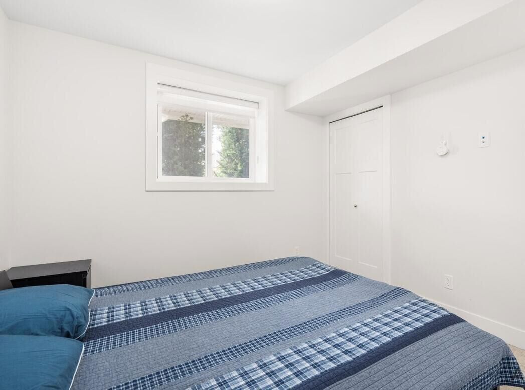 A bedroom with a bed, a window, and a door.