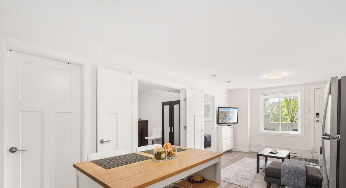 A modern kitchen with white cabinetry, a wooden countertop, and a built-in oven.