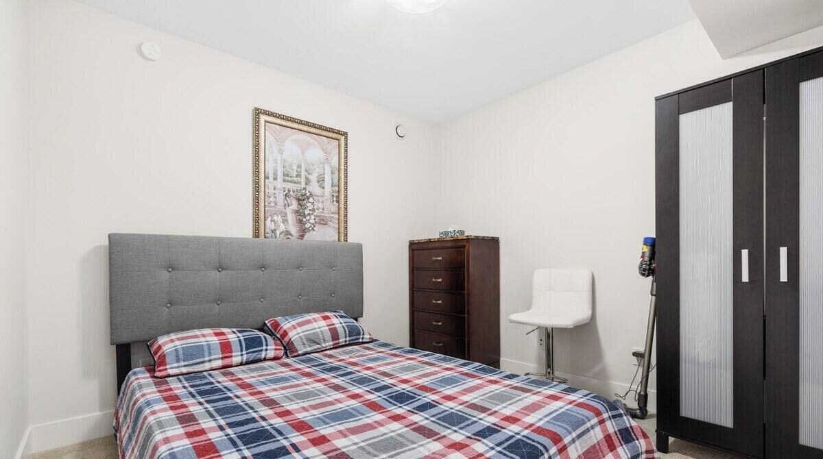 Ein Schlafzimmer mit einem Bett, einem Kleiderschrank, einem Nachttisch und einer Wandlampe.