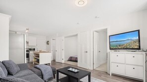 A modern living room with a sofa, a coffee table, and a television. - Modern 2BR Suite Near Lonsdale & Mountains (North Vancouver)