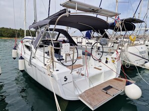 A sailboat docked at a marina with a covered deck area, a steering wheel, and a winch. - Sun-Kissed Sailing: An Unforgettable Beach Experience in Istria, Croatia (Medulin)
