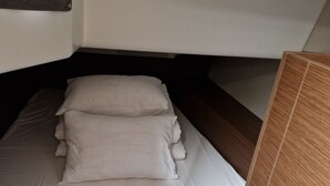 Pieni, käytännöllinen sänky valkoisilla vuodevaatteilla, sijoitettu mökkihenkiseen sisustukseen.