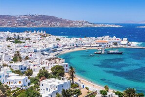 A coastal town with white buildings, a beach, and boats in the water.