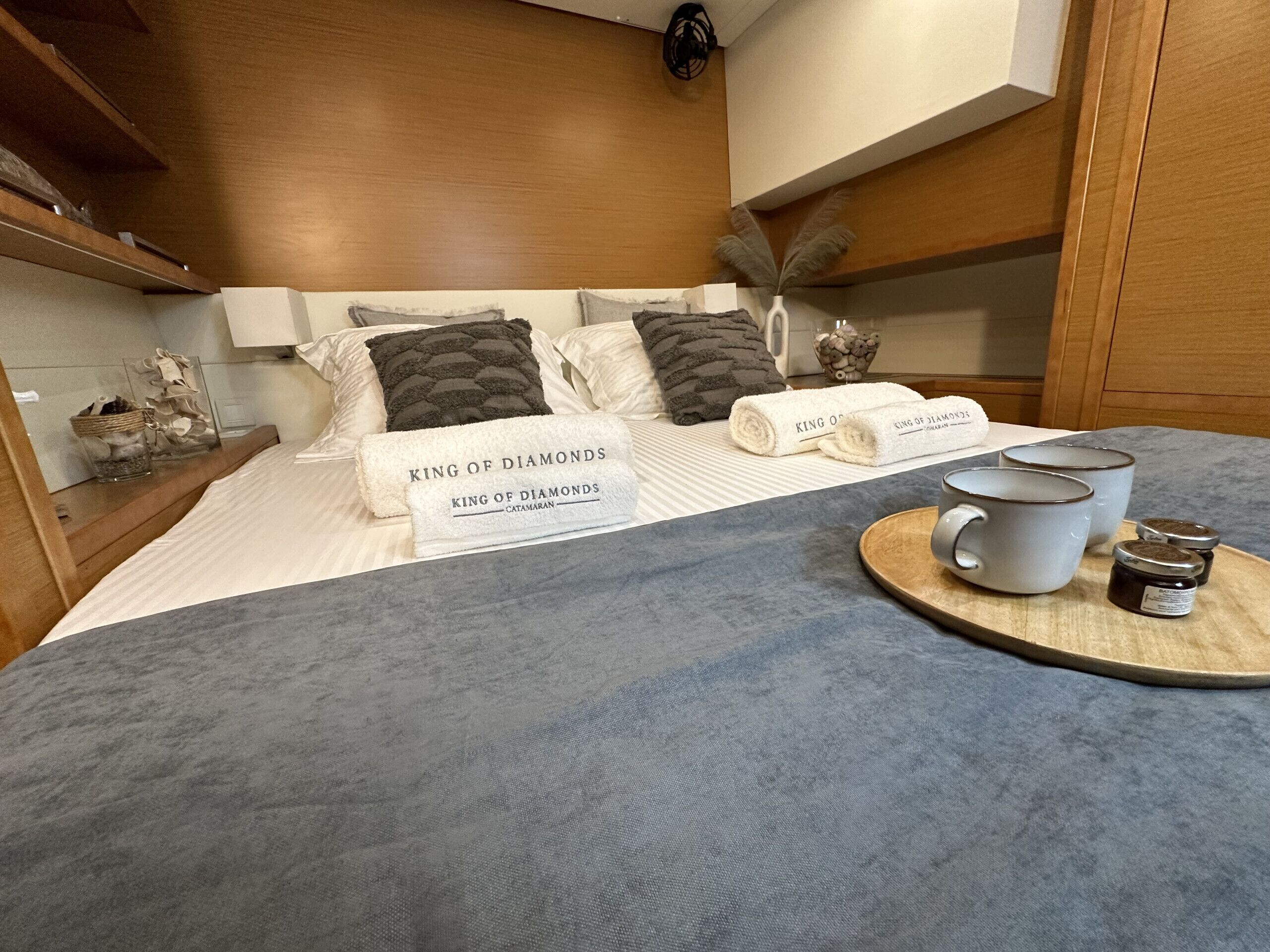 Ein Hotelzimmer mit einem Bett, Kissen, einem Tablett mit Tassen und Gläsern sowie einem Schild auf dem Bett.