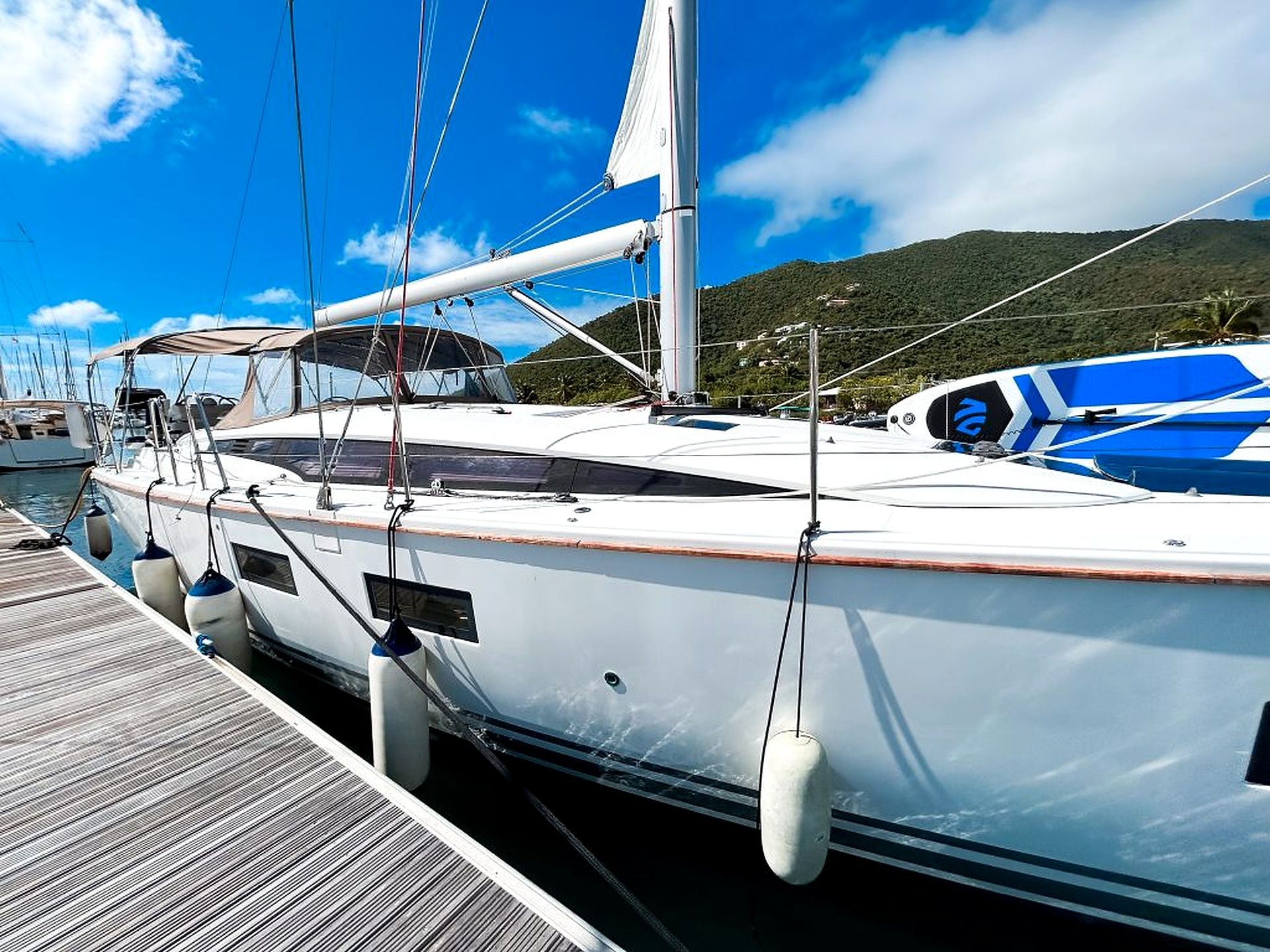 Un yacht blanc était amarré dans une marina, avec un pont en bois et une chaîne de montagnes en arrière-plan.