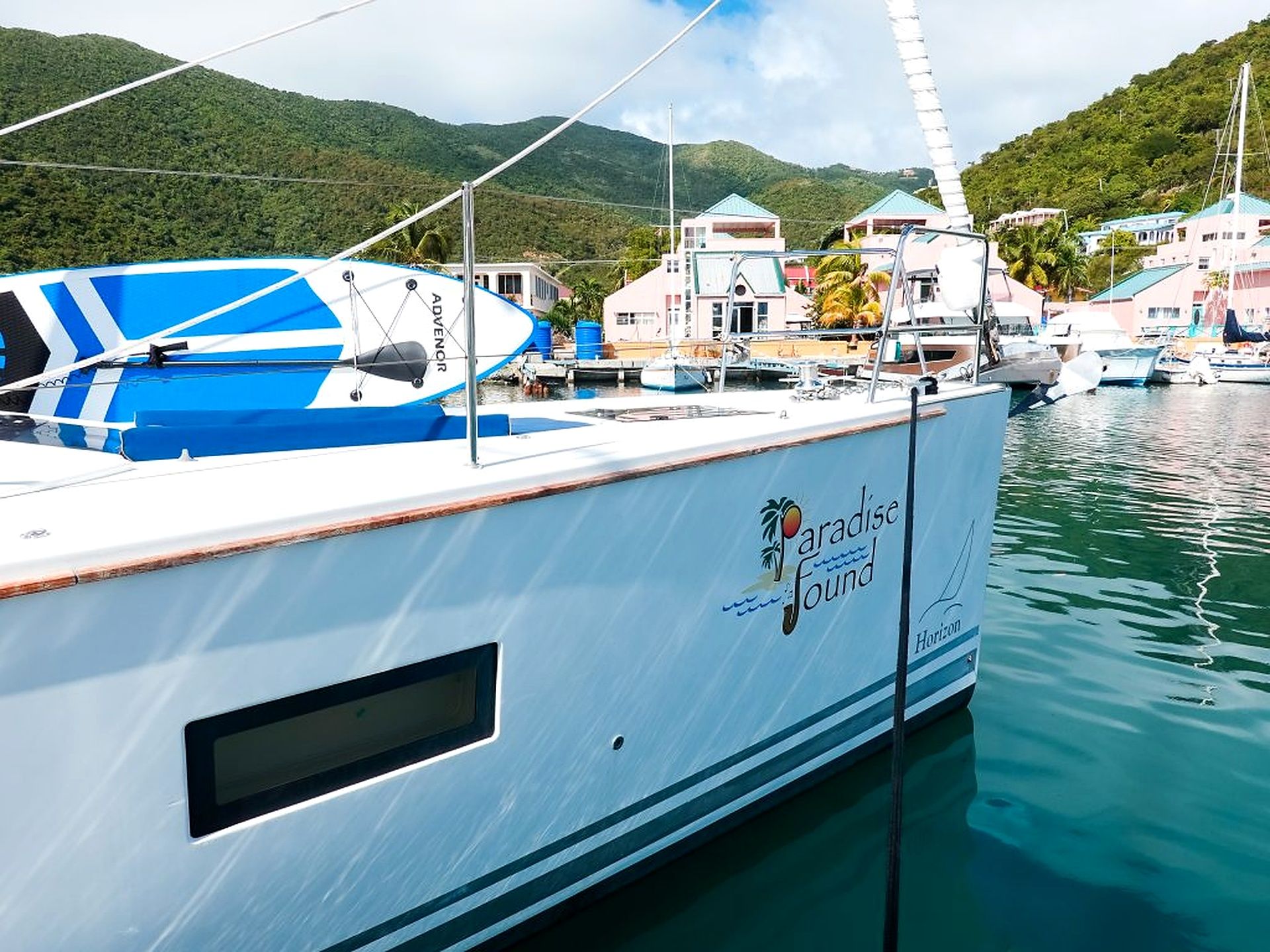A large yacht docked at a marina with a logo that reads 'Paradise Found.'