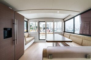 A modern interior with a dining area, seating, and a view of the marina. - Sun-Kissed Sailing Adventure in the Ionian Islands, Lefkada (Lefkada)