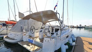 A sailboat docked at a marina with a covered deck, a steering wheel, and a 'UAGUE ZADAR' sign. - Sun-Kissed Sailing Adventure in Zadar, Croatia (Zadar)