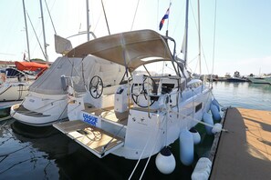 A sailboat docked at a marina with a covered deck, a steering wheel, and a 'UAGUE ZADAR' sign. - Sun-Kissed Sailing Adventure in Zadar, Croatia (Zadar)