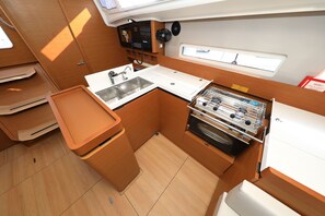 A compact kitchen with a sink, stove, and storage cabinets. - Sun-Kissed Sailing Adventure in Zadar, Croatia (Zadar)