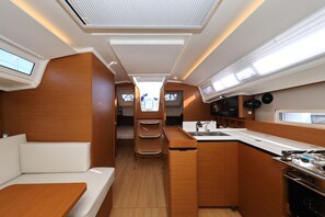 A compact kitchen with a sink, stove, and storage cabinets, a small seating area with a bench, and a skylight above. - Sun-Kissed Sailing Adventure in Zadar, Croatia (Zadar)