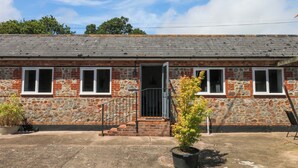 A stone building with a brick facade, a set of stairs leading to a door, and a potted plant in the foreground. - The Milk Shed (Cullompton)