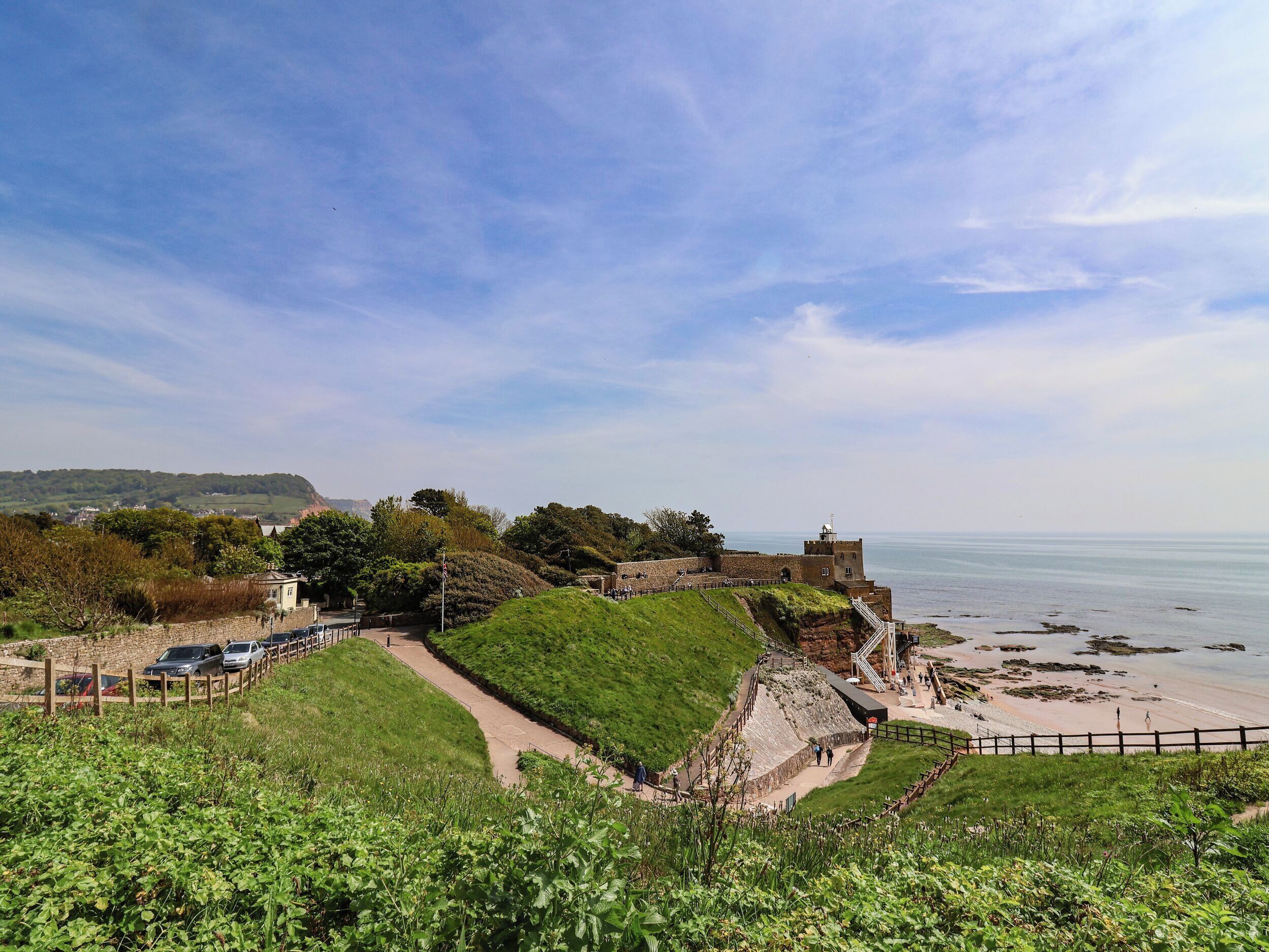 A coastal fortification with a grassy path leading to a beach, overlooking the sea.