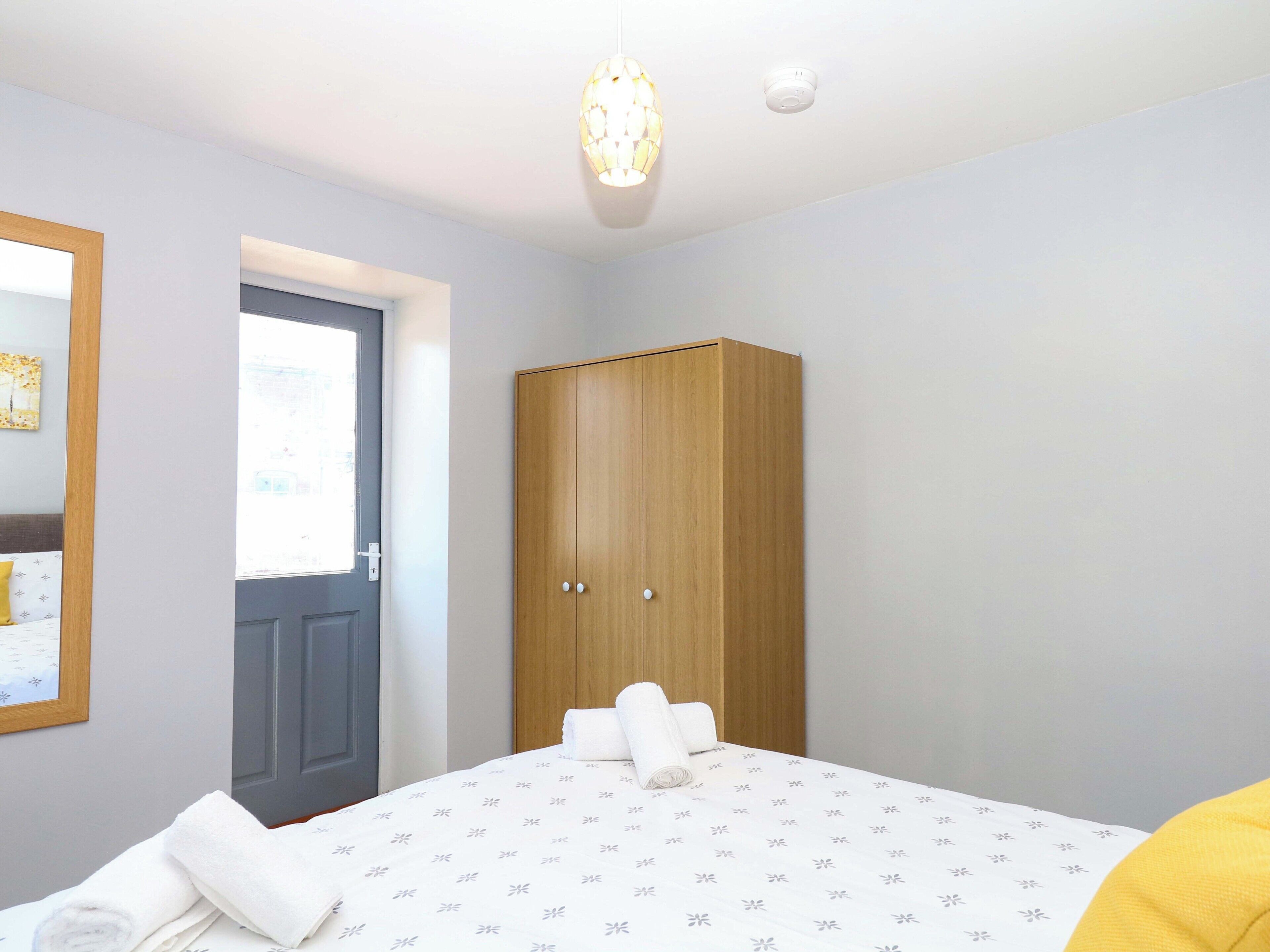 A bedroom with a bed, a wardrobe, a door, and a light fixture.