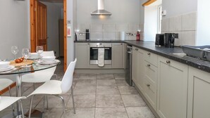 A modern kitchen with a dining area, stainless steel appliances, and a wooden ceiling. - The Milk Shed (Cullompton)