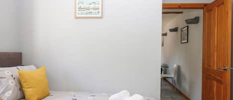 Ein Schlafzimmer mit einem Bett, einer Holztür und einem gerahmten Bild an der Wand.