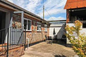 A residential property with a stone facade, a brick chimney, a metal gate, and a patio area with outdoor furniture.