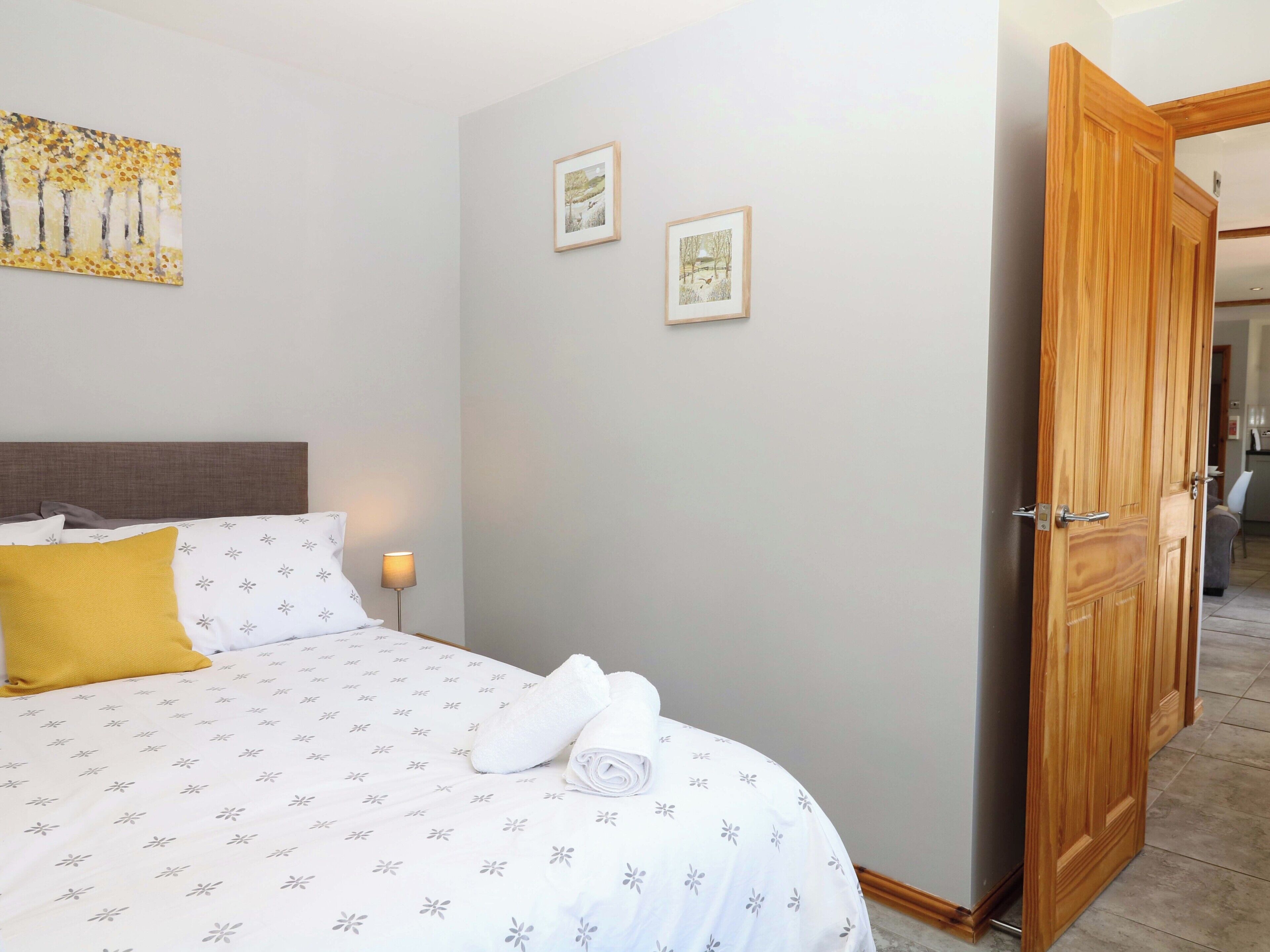 Un dormitorio con una cama, una mesita de noche, una lámpara y dos cuadros en la pared.