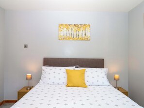 A bedroom with a bed, two bedside tables, a nightstand, a headboard, and a wall-mounted painting. - The Milk Shed (Cullompton)